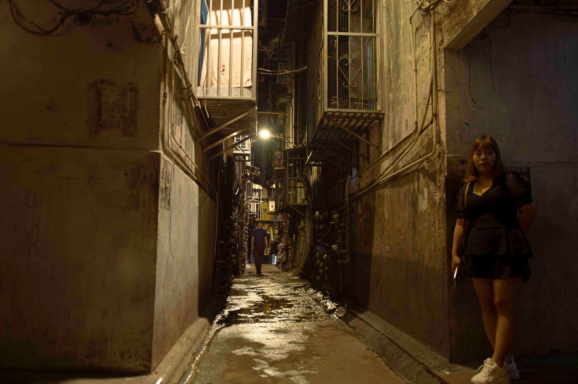 A-woman-waits-outside-her-apartment-down-an-alley-in-central-Macau.-Image-via-That-s-Lars-Hamer.jpeg