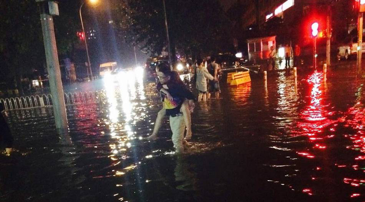 A man piggybacks a woman through the flooded streets of Beijing