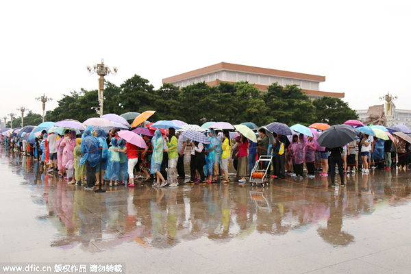 Tourists line up in the rain outside Tiananmen Square